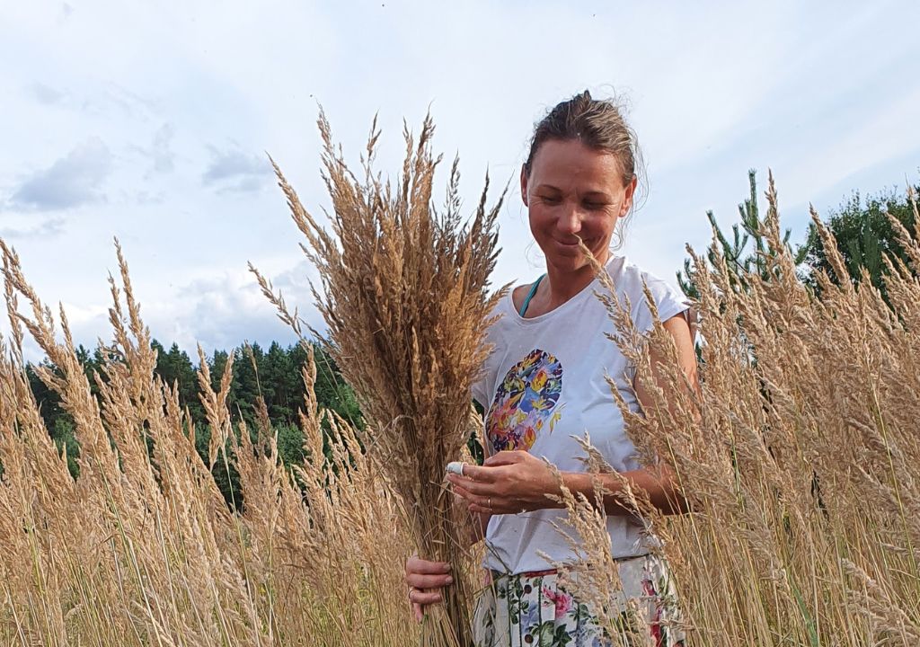 Medaus Žemės įkūrėja Erika su lauko gėlių ir smilgų puokšte Dzūkijos miškų fone